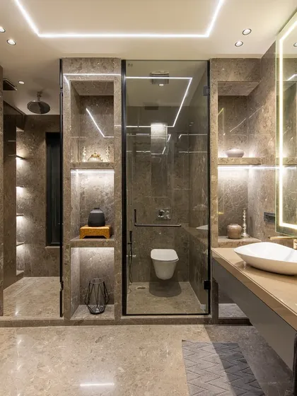 A full view of a modern bathroom, showcasing the floating vanity, back-lit mirror, and the glass-enclosed shower and toilet stalls. The grey-toned wardrobe doors on the left provide ample storage.