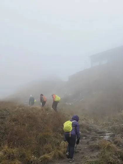 Trekkers navigate a misty, high-altitude trail on the way to Annapurna Base Camp. The challenging weather only adds to the sense of adventure.