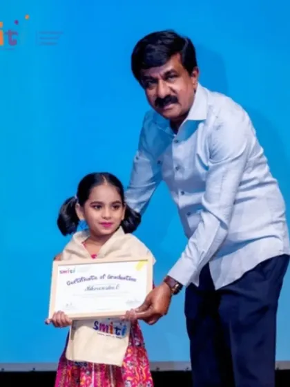 A graduate smiles for the camera as she receives her certificate. This moment marks the culmination of her Montessori journey with us.
