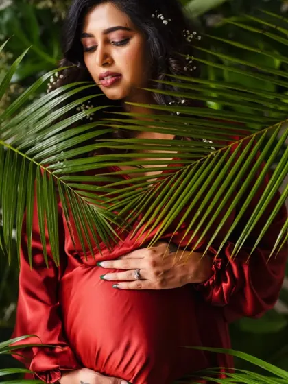 A lush, tropical-themed portrait with the mother-to-be framed by palm leaves.
