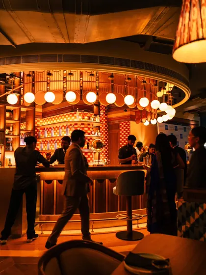 Another perspective of the bustling bar at Comorin. The warm, ambient lighting and the movement of the patrons give a sense of the restaurant's vibrant nightlife.