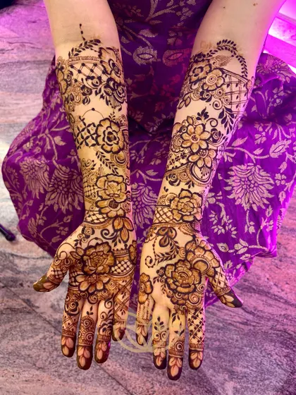 The full view of the floral-themed bridal mehendi, showcasing the delicate roses and vines that cover the hands and arms.