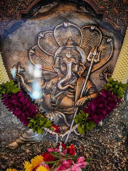 A beautifully carved Ganesha relief, adorned with garlands for the festival. Ganesha is revered as the remover of obstacles and the lord of new beginnings.