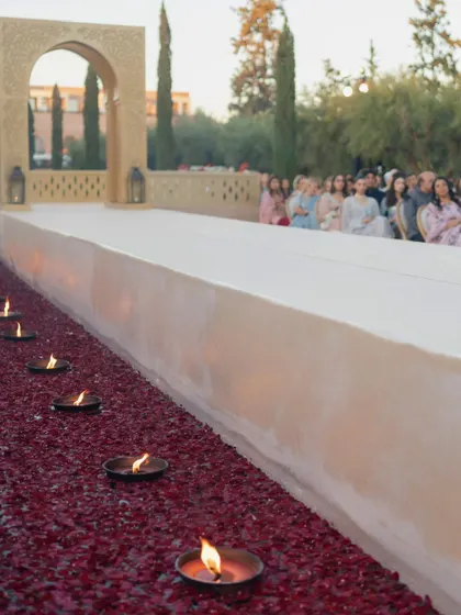 The wedding aisle along the grand canal in Marrakech, lined with hundreds of diyas floating in water filled with red rose petals.