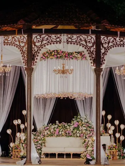 A closer look at the reception gazebo stage, where a custom chandelier made of floral and crystal strings hangs above a sofa enveloped in pastel blooms.