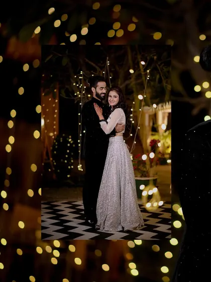 A romantic shot of the couple framed by the warm glow of fairy lights.
