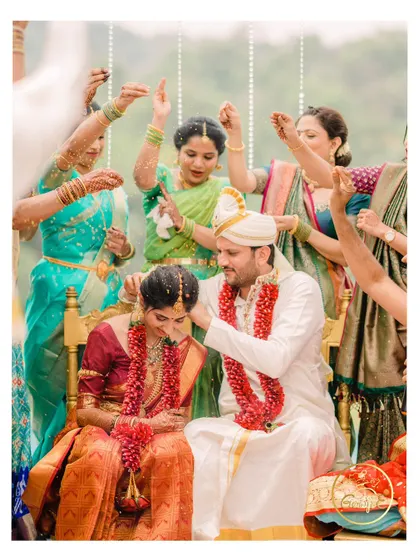 A joyful moment from a traditional South Indian wedding, where the couple is showered with blessings by their family.
