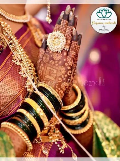 The beautiful dark stain of a bridal backhand design, complemented by the bride's green bangles.