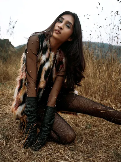 A confident and stylish pose in an outdoor setting. The natural, muted tones of the background make the model's outfit pop.