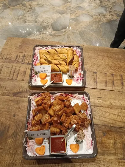 A platter of classic crowd-pleasers. We serve crispy Veg Spring Rolls and savory Gold Coin appetizers, both fried to golden perfection and accompanied by a sweet and spicy dipping sauce.