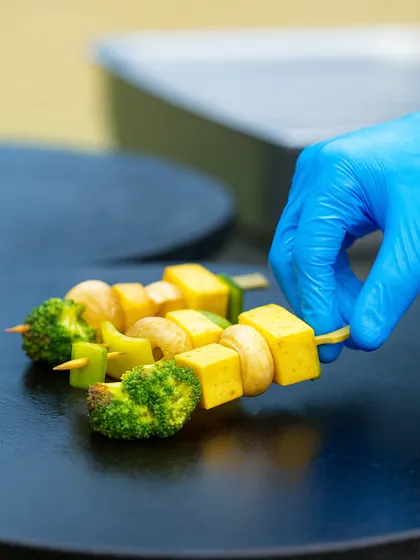 A chef prepares a vegetable and paneer skewer on the grill. Our live cooking stations are an interactive part of our celebration brunches, adding to the festive atmosphere.