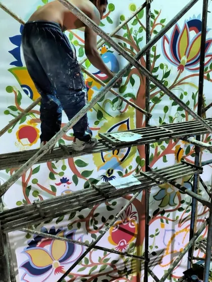 My talented team member working high up on the scaffolding, adding details to the Kalamkari mural. Large-scale projects are always a team effort.
