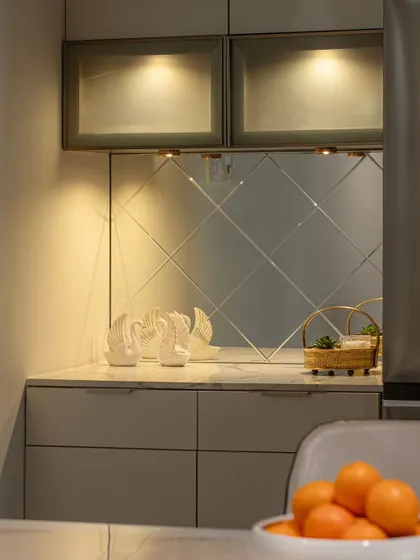 A detail of the 'Blue Elegance' crockery unit, showcasing the beveled mirror backsplash and under-cabinet lighting that creates a warm, luxurious glow.