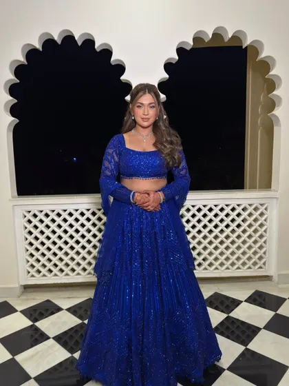 The full view of this royal blue Sangeet outfit. The makeup and hair are designed to create a harmonious and striking overall look.