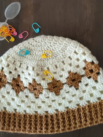 This is my Diamond Granny hat, a unique take on the classic granny stitch. The stitch markers show my work in progress as I was designing the pattern.
