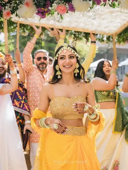A radiant bride making her entrance, surrounded by loved ones. The floral canopy she holds is a beautiful, portable piece of decor that adds to her glow.