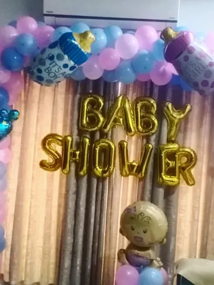 A simple and sweet baby shower decoration for a home setting. The balloon arch with foil baby-themed balloons creates a festive atmosphere instantly.