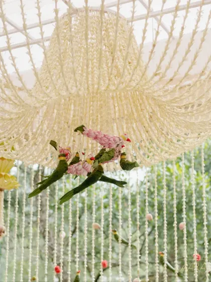 A whimsical detail from the 'Pastel Panchangam' theme: parrots crafted from leaves and flowers hang from a jasmine chandelier, adding a touch of nature-inspired artistry to the decor.