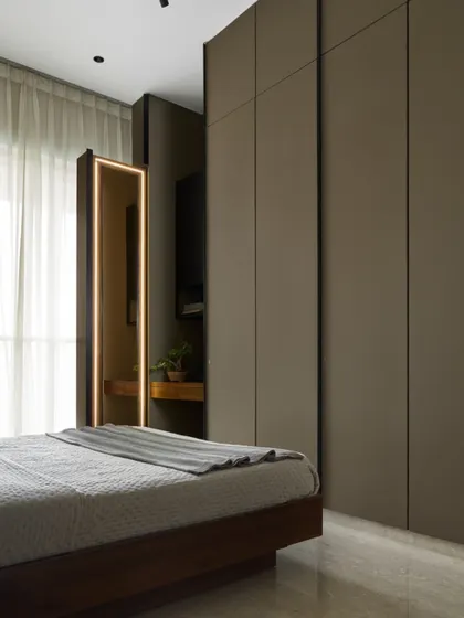 A static view of the Taupe Bedroom in Lumen House, where the sleek, floor-to-ceiling wardrobe panels conceal a compact dressing unit. This integration of function is key to our minimalist approach.