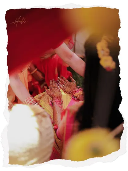 An artistic shot of the bride's henna-covered hands during the Haldi ceremony, framed in a creative torn-paper effect.