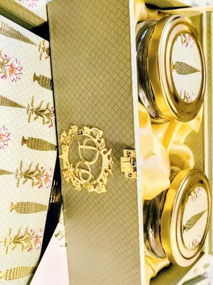 An inside look at the mint green invitation box, revealing two beautifully labeled jars ready to be filled with gourmet nuts or sweets. The satin lining adds an extra layer of luxury.