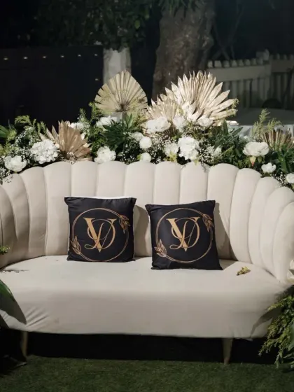 The happy couple deserves a special spot. We created this elegant seating area for the bride and groom at their Sangeet, featuring a classic white sofa, lush floral arrangements, and custom monogrammed pillows.