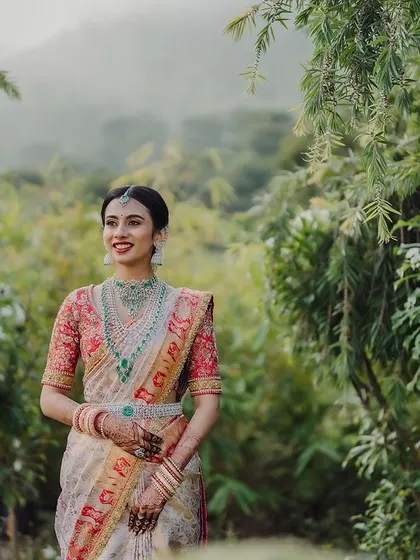 The serene beauty of a bride in nature. Prathima's radiant look stands out against the lush greenery, a testament to makeup that enhances beauty without overpowering it.