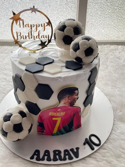 A Cristiano Ronaldo-themed football cake. The design features a soccer ball pattern, edible player image, and handcrafted chocolate footballs.