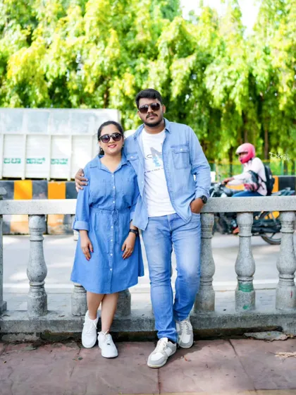A casual and cool pre-wedding photo of a couple in matching denim outfits, shot on a city bridge.