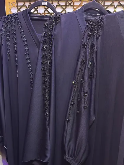 The sleeve details on these dark navy abayas are incredible. One features a climbing vine of black beads, while the other has a more abstract floral beadwork design.