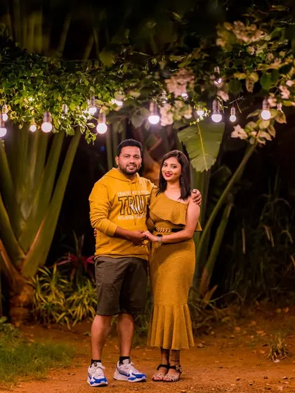 A sweet, casual moment in a garden path lit by hanging bulbs. This shot captures the warmth and intimacy of the couple's connection.