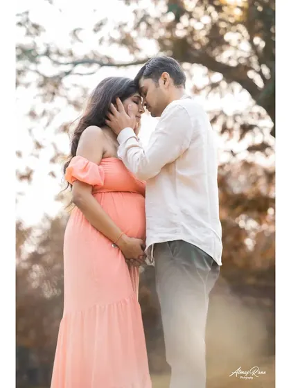 A tender moment between expecting parents, framed by the soft light of the outdoors. This image focuses on their closeness and the shared anticipation of welcoming their third family member.