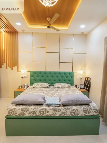 A serene master bedroom from the Tambaram project, with a tufted green headboard, a custom bed, and a stylish wall paneling design with golden accents.