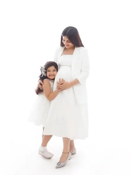 A sweet mother-daughter portrait during a maternity session, with the daughter hugging her mother's baby bump.