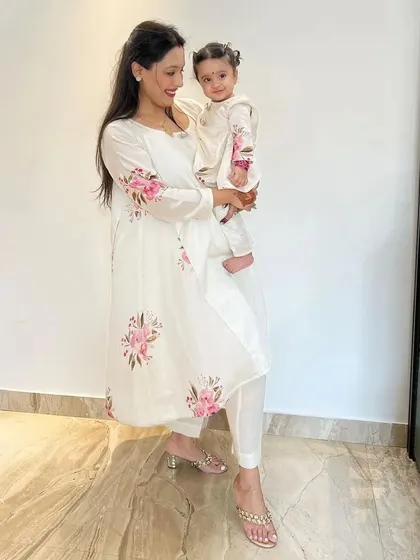 Elegance in white and pink. This mother and daughter are wearing matching hand-painted floral kurta sets, a graceful choice for family gatherings, pujas, or any special occasion.