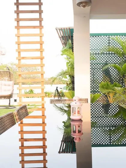 A closer look at the dining area in this terrace garden. The reflection on the glass tabletop beautifully mirrors the green privacy screen and the sky, making the space feel open and connected to the outdoors.