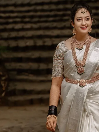 A candid shot of a bride in a white saree walking with a smile, capturing her natural grace and happiness on her wedding day.
