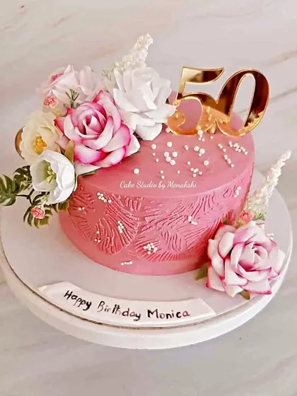 A stunning 50th birthday cake in vibrant pink, made with zero fondant. The textured buttercream and beautiful floral arrangement make this a true showstopper.