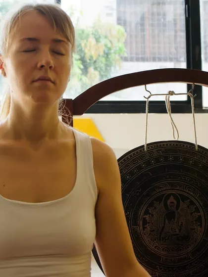 A participant in quiet meditation, with a gong in the background.