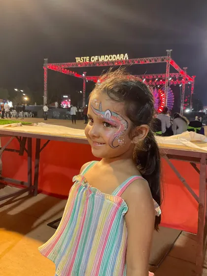 A little girl smiling with her sparkly unicorn face paint at the Taste of Vadodara event.