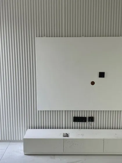 A work-in-progress view of a family lounge transformation. This image highlights the installation of a fluted wall panel and a minimalist TV console, laying the groundwork for a clean, contemporary aesthetic.