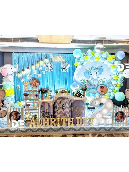 A grand baby elephant theme for Adhrith Dev's second birthday. The setup includes large elephant cutouts, a light-up number '2', and personalized photo displays.