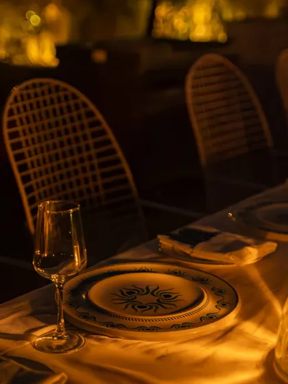 A close-up of a single place setting at a fine-dining restaurant. The focus on the custom plate and the soft, warm light creates an elegant and inviting feeling.