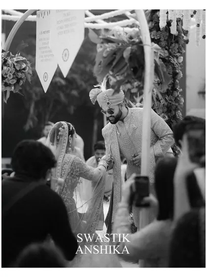 A candid black and white moment from the ceremony. This shot, taken from the perspective of a guest, captures the couple's connection and the reality of being surrounded by loved ones.