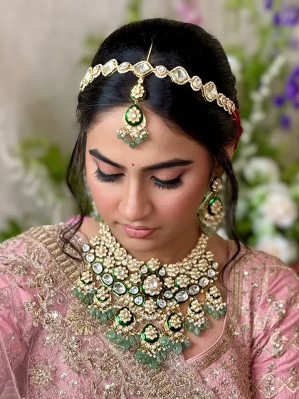 A detailed shot of the eye makeup and matha patti. The soft pink and shimmer on the lids make her eyes pop, while the jewelry adds a touch of tradition.