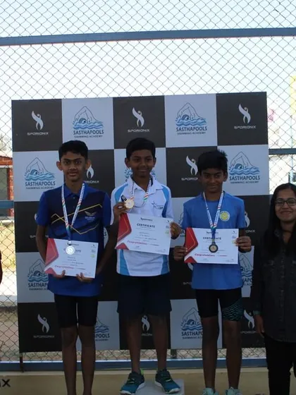 The top three finishers of a swimming event stand on the podium for their awards.