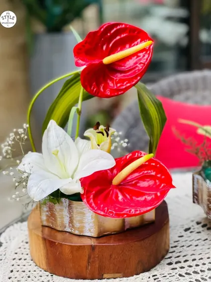 This urli arrangement features exotic red anthuriums and white lilies. The combination of bold and delicate flowers creates a magical appearance that is both modern and delightful.