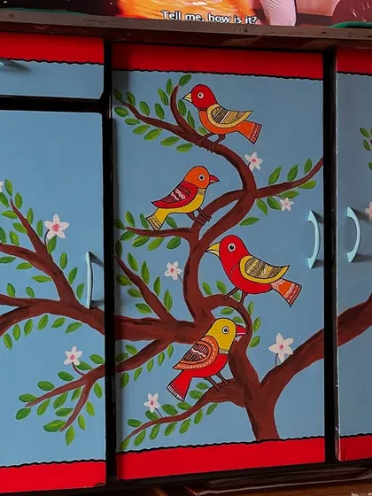 I gave this old cupboard a complete makeover with a vibrant, hand-painted mural. The design features colorful birds perched on a flowering tree, turning a functional piece of furniture into a statement art piece for the home.
