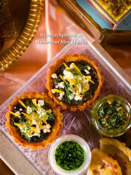 A savory Ricotta, Spinach & Mushroom Mini Quiche, garnished with fresh dill and crumbled cheese. A perfect bite for any festive occasion.