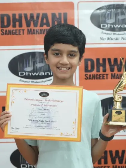 A smiling student holds up his certificate and trophy after the award ceremony.
